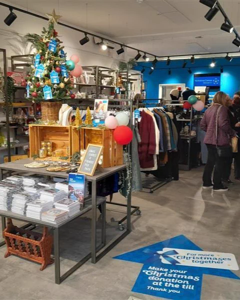 Inside the Yorkshire Cancer Research shop in Northallerton, decorated festively with a Christmas tree, cards and gifts visible.