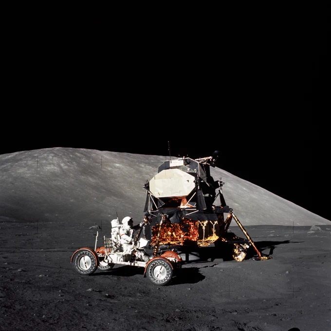 Lunar module and lunar roving vehicle, with an astronaut at the controls, are pictured together on the Moon.
