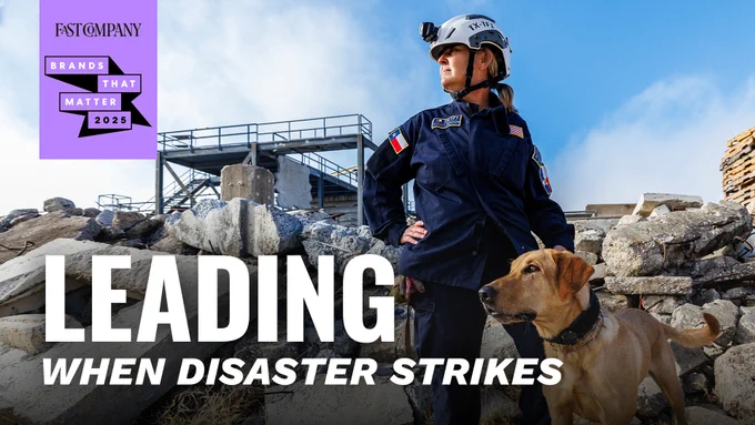 An image featuring a search and rescue worker in uniform, accompanied by a trained dog, standing in a rubble-strewn area. The backdrop displays a sign with the text 'Fast Company Brands That Matter 2025' and the caption 'LEADING WHEN DISASTER STRIKES'.