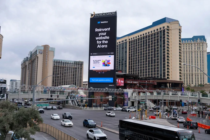 A photo of a billboard on the Las Vegas Miracle Mile taller than a huge building next to it.