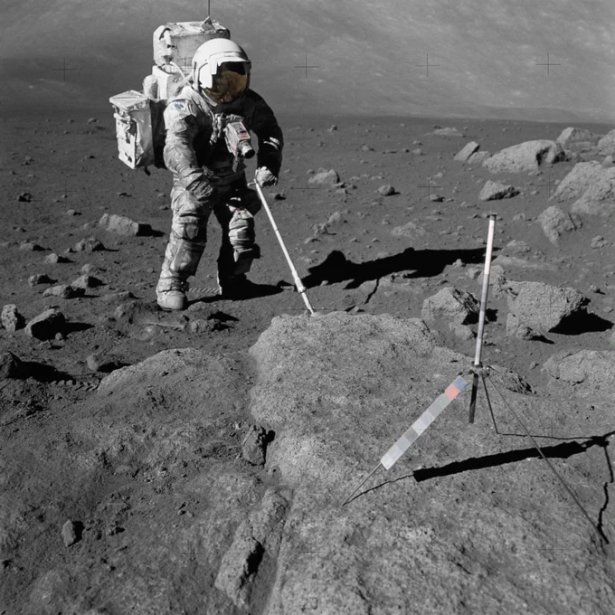 Scientist-astronaut Harrison Schmitt, Apollo 17 lunar module pilot, uses an adjustable sampling scoop to retrieve lunar samples during the second Apollo 17 Extravehicular Activity (EVA 2), at Station 5 at the Taurus-Littrow landing site. In the foreground is a gnomon, a device used to help calibrate color and size for field photographs.