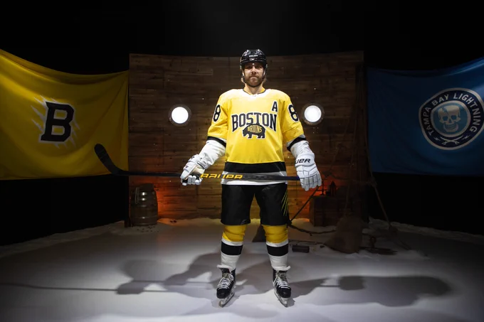 David Pastrnak donning the Bruins gold Stadium Series uniform with white gloves.
