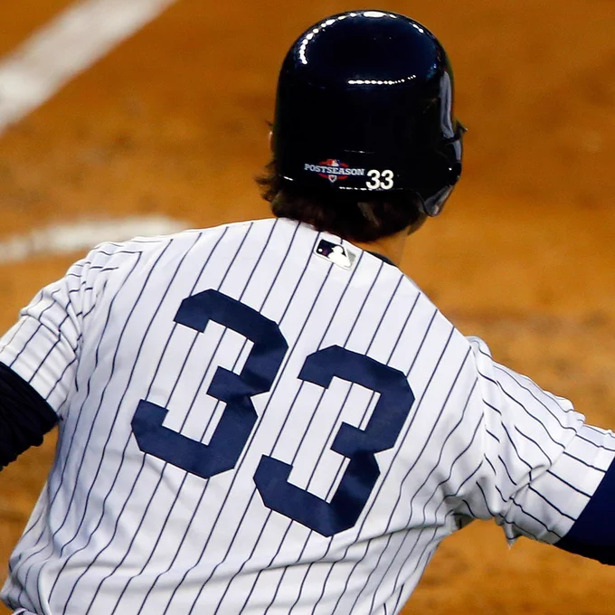 A photo from behind of Nick Swisher during the 2012 Postseason. He is wearing a #33 pinstriped New York Yankees jersey and a dark blue Yankees batting helmet with the #33 on the back.