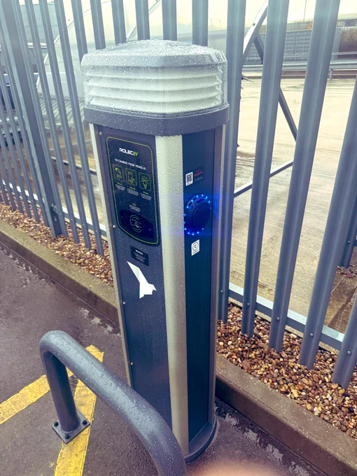 The charger shown in the image is a Rolec Quantum pedestal-style EV charging unit, designed for commercial and public environments. This model features a durable, weather-resistant enclosure with a vented top housing to protect internal electronics and ensure thermal stability. The front interface panel provides RFID activation, QR-code app access, and clear user instructions for starting and stopping a charge session.

The illuminated charge port on the right side indicates status through LED ring lighting, supporting quick visual checks for availability, charging, or fault conditions. The Quantum range typically supports fast AC charging—commonly 7.4kW or 22kW per socket—via Type 2 connectors, making it suitable for workplace, fleet, and public car park installations.

Built to OCPP standards, the unit can be networked with back-office systems for monitoring, billing, and load management. Internal electrical components are protected by impact-resistant casing, integrated protection.