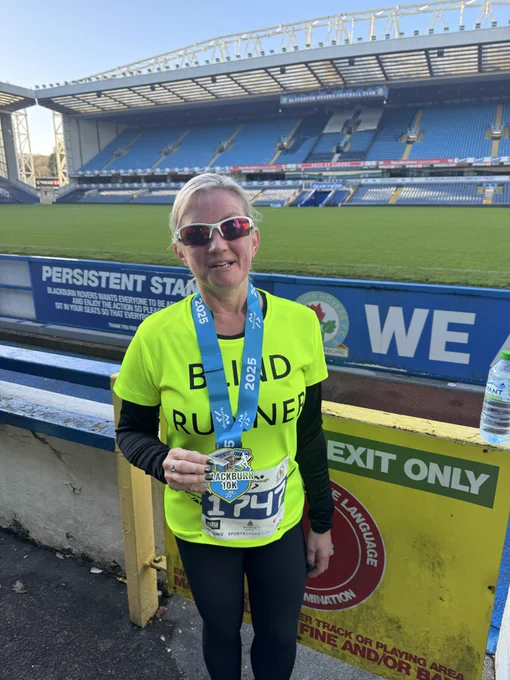 Kelly stood with medal in front of the ground