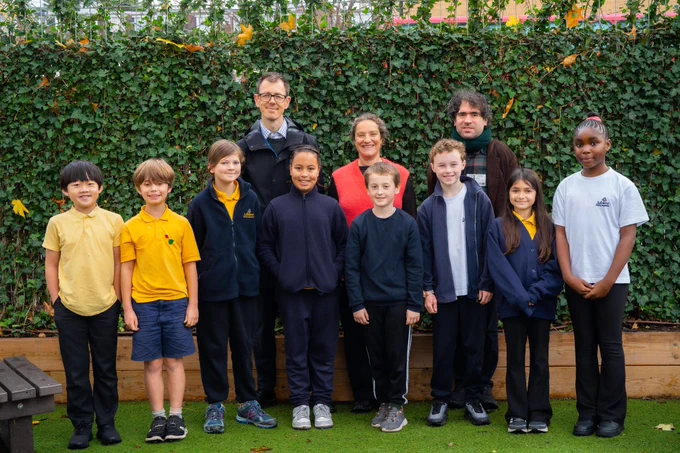 School children, Cllr Sarah Young, Cabinet Member for Climate, Environment and Transport, Cllr Sam Pallis, Councillor for Cazenove Ward stand in front of a screen of foliage at Jubilee Primary School