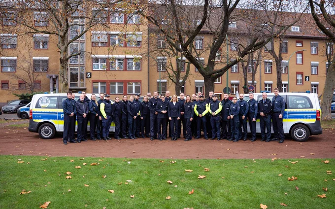 Gruppenbild mit zwei Einsatzfahrzeugen, Polizistinnen und Polizisten sowie der Polizeipräsidentin.