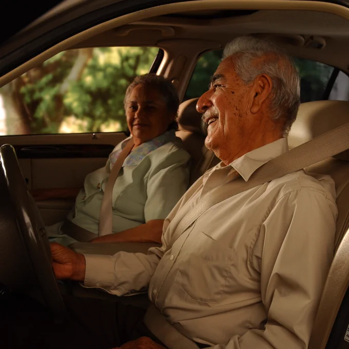 An older couple in a car wearing seatbelts.