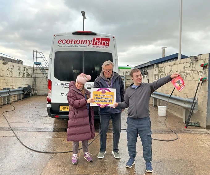 Students standing by a minibus holding a specialist FE sign
