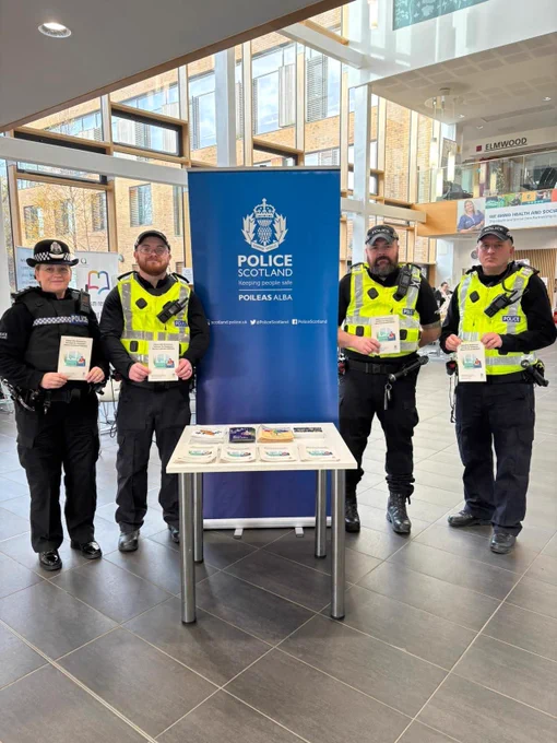 An image of 4 police officers standing next to a blue banner with white text "Police Scotland" and a small table containing leaflets.