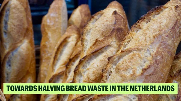 Fresh baguettes on display with a caption reading 'Towards Halving Bread Waste in the Netherlands.'