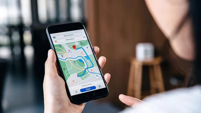 a woman holing a cell phone looking at GPS.