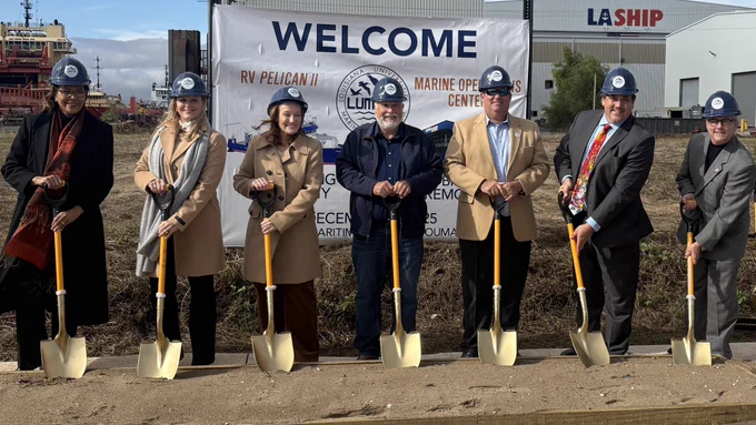 Seven people stand outside holding gold shovels
