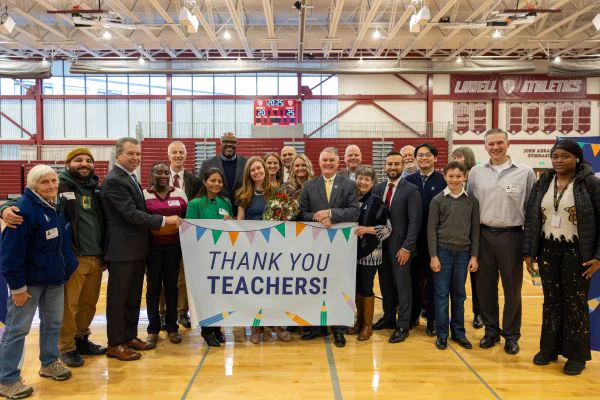 Tara Goodhue and state and local partners and friends stand behind a banner that says "Thank you Teachers!"