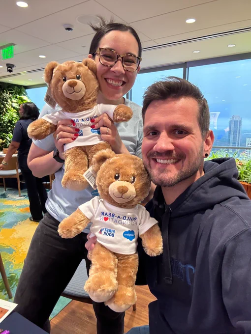Two employees hold stuffed animal bears.