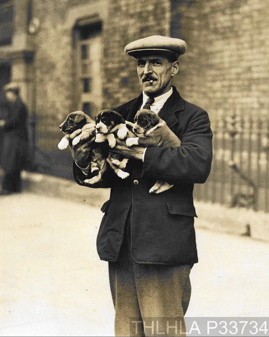 Black and white photo of a man selling puppies at Club Row Market circa 1925.