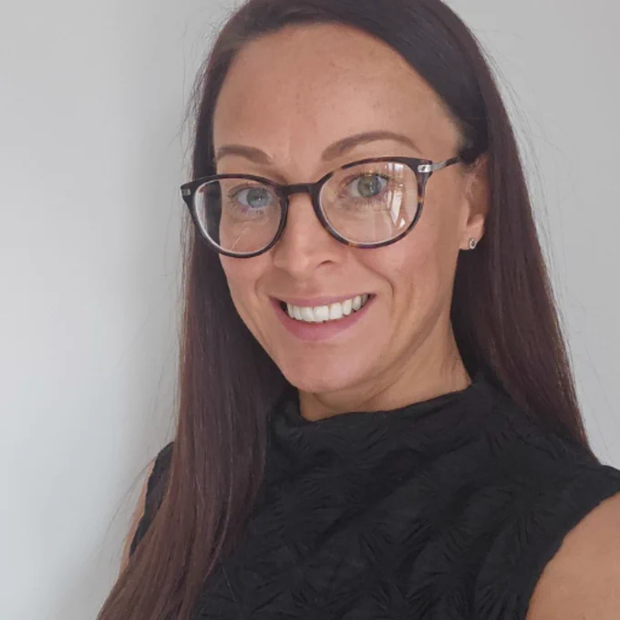 A photograph of DDU adviser Rachael. Rachael is wearing a black top and glasses and smiling at the camera.