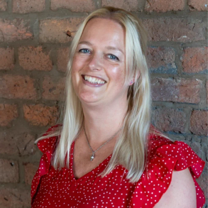 A photograph of DDU adviser, Miranda. Miranda is wearing a red polka dot top and a silver necklace, and is smiling at the camera.