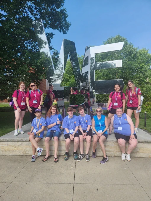Students and staff from OVR's summer academies smile for a photo in front of a "We Are" Penn State statue. 