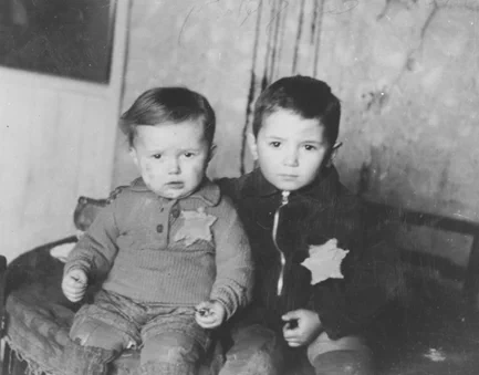 A portrait of Emanuel Rosenthal, age two, and his brother, Avram, age five in the Kovno ghetto, Ukraine, February 1944. They wear Jewish badges. The little boys’ uncle, Shraga Wainer, had asked fellow ghetto prisoner, George Kadish to photograph the boys. Weeks later, both children were murdered in the "Children's Action” of 27-28 March. The photograph endures, reflecting an uncle’s love and an insistence on preserving humanity against the antisemitic efforts to erase it. Credit: United States Holocaust Memorial Museum, courtesy of Shraga Wainer 