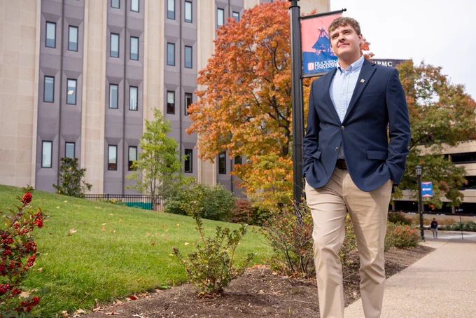 Nick Miller walks next to College Hall