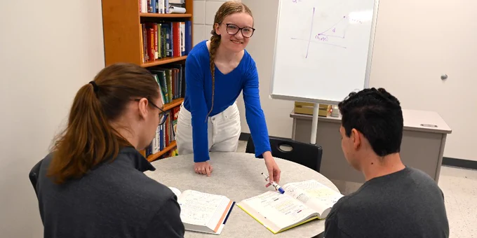 A tutor meets with two people. 