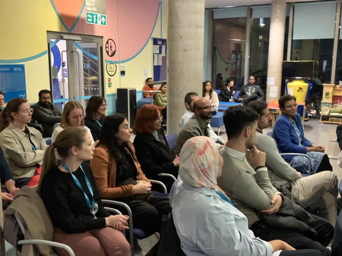 The audience at the ophthalmology clinical academic trainee forum engaging in discussion. Audience members are sat in rows in chairs facing the speaker.