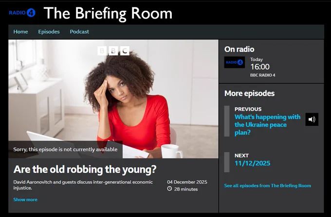 A woman with curly hair sits at a desk in a bright modern room, resting her head on one hand with a tired expression while looking at papers spread out in front of her. She wears a red top and has a mug nearby. The BBC Radio 4 webpage around her shows the programme Are the old robbing the young with the broadcast set for 16:00 on 04 December 2025. The page includes a dark header, a large central image, a message stating the episode is not currently available and side panels with links to previous and upcoming episodes.