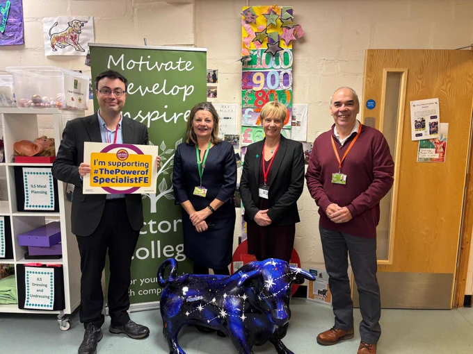 Clare and Laurence Turner MP alongside Victoria College staff including Principal Clare Scattergood. Laurence is holding an I'm supporting the Power Of Specialist FE pledge board. A starry painted bull (Victor) is at their feet. 