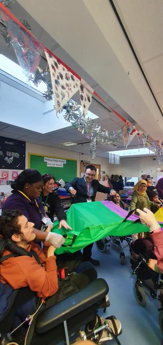 Photo of a group of students getting a ball across a raised sheet.