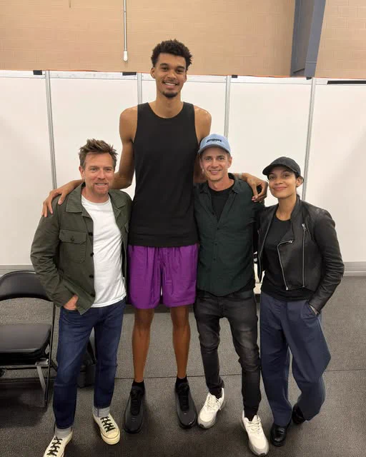 A few Star Wars actors standing next to an abnormally tall person. 