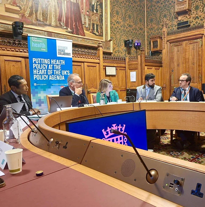 Panel discussion in the House of Lords sitting at a curved table, featuring a banner reading 'Putting Health Policy at the Heart of the UK's Policy Agenda.'