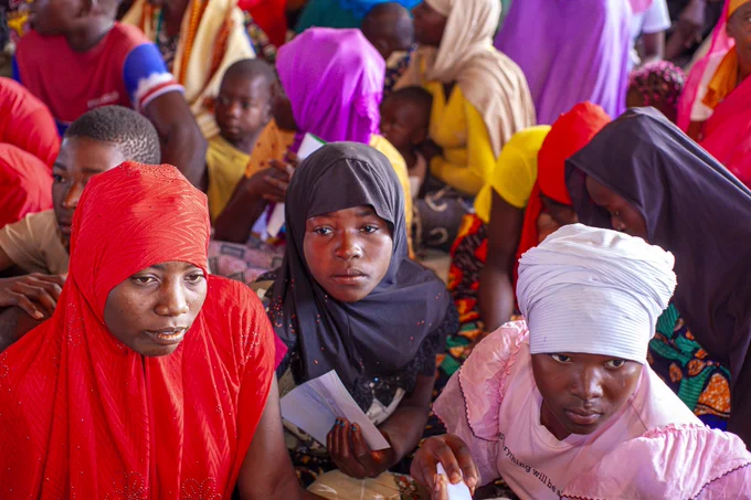A group of displaced girls in northern Mozambique seated on the floor in an accommodation centre.
