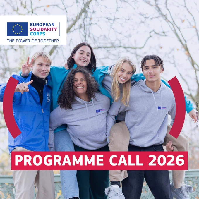 A group of five smiling young people stand closely together outdoors, wearing European Solidarity Corps hoodies and jackets. They pose with arms around each other. The European Solidarity Corps logo appears in the top left, and bold red text reads ‘Programme Call 2026.’