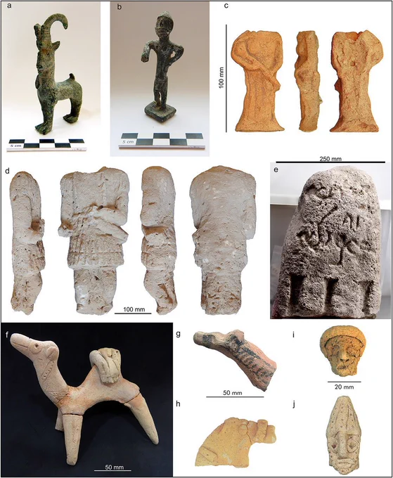 Copper-alloy and terracotta figurines depicting animals and humans, a stone statue of a human with the head missing, and a stone engraved with an Aramaic inscription.