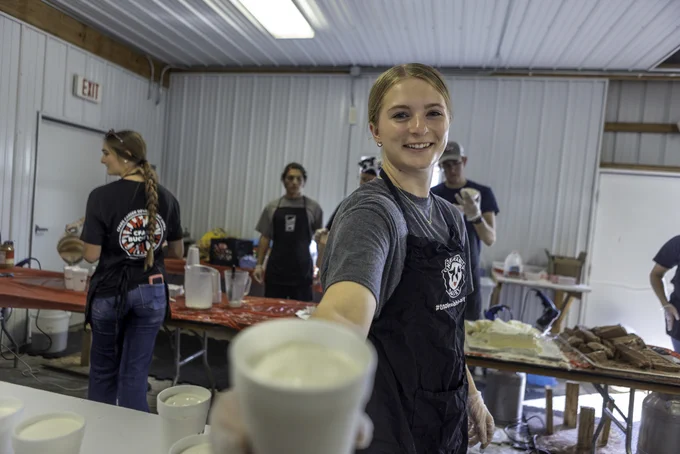 A Buckeye Dairy Club student holding a milkshake toward the camera.