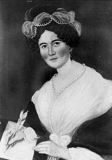 A black and white picture of a portrait of Catharine Read Williams, she is looking up and writing with a quill.