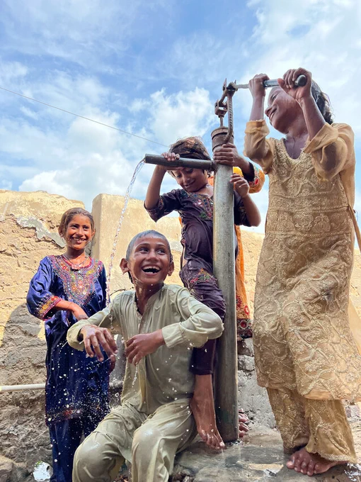 Children cool off under a water pump in their village in Sindh province, Pakistan.