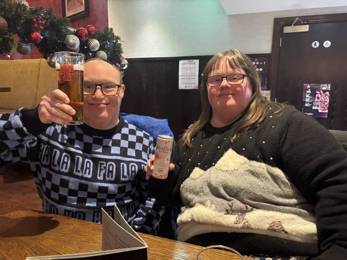 Jonathan and Catherine holding up their drinks and saying cheers