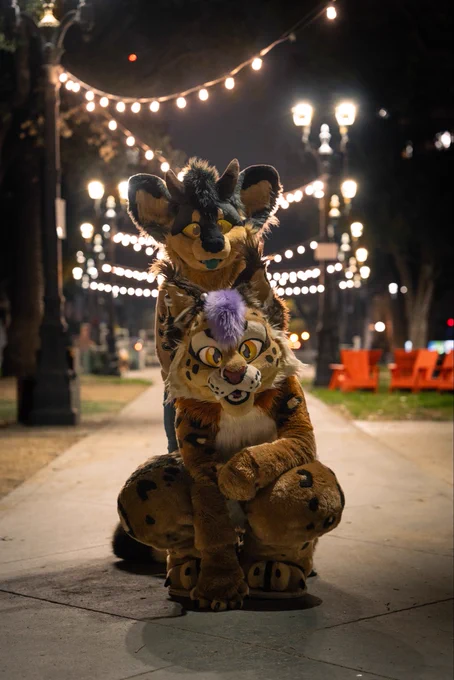 Emerald and Kotoro standing center frame in a park, lights behind them.