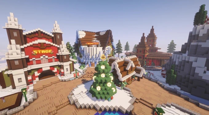 In this image is a large christmas stage with a tree in the center. In the background is a few christmas buildings with a snowy mountain on the right.