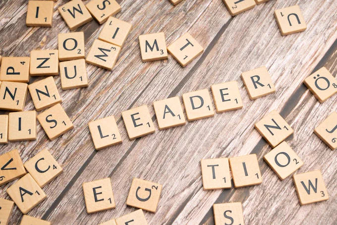 Wooden Scrabble tiles on a table spelling 'Leader' symbolize leadership and strategy.