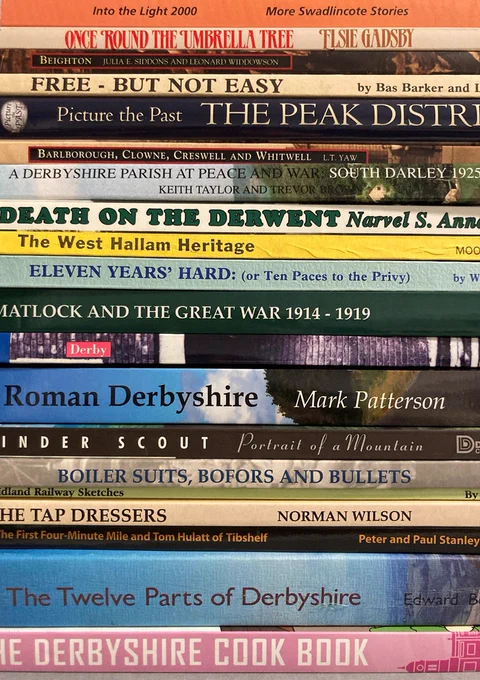 Colourful close-up image of the spines of a stack of books. They include titles such as 'Death on the Derwent', 'The West Hallam Heritage', 'Roman Derbyshire' and 'The Twelve Parts of Derbyshire'.