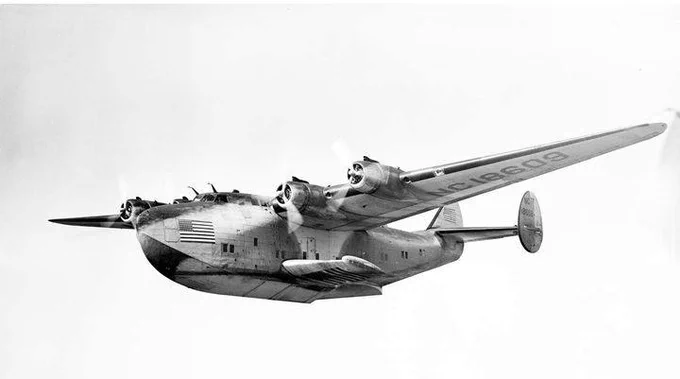 A flying boat type of aircraft is pictured from the side during flight.