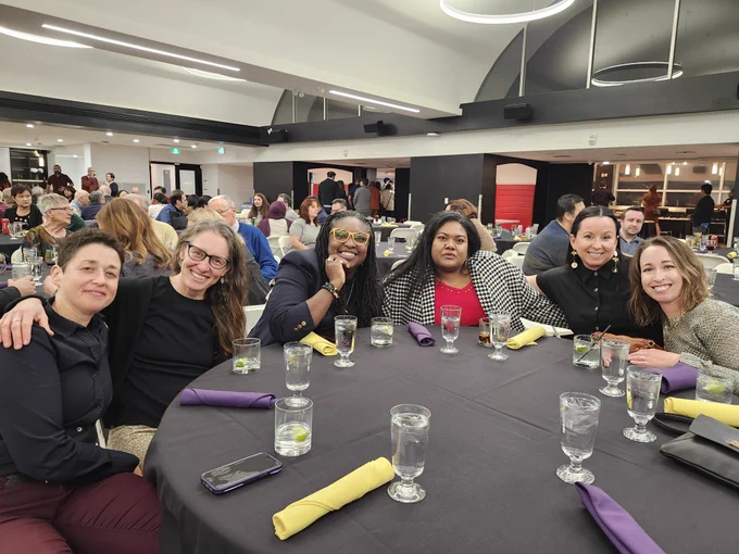 Six WLUFA Members smiling for a photo at their table near the front of the room.