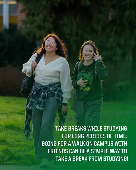 Two students are walking on a university campus, smiling and enjoying a break from studying.