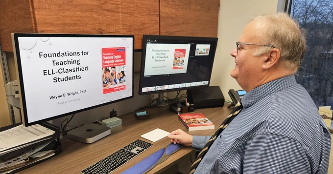 Man presenting at desk with slide in background with text "Foundations for Teaching ELL-Classified Students"