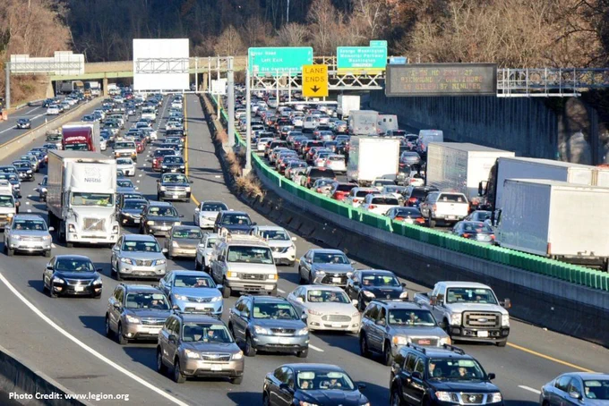 Traffic congestion on American Legion Bridge, with multiple lanes of vehicles in both directions, including trucks and cars, under clear skies. Signs visible for lane directions and exits. Photo credit: www.legion.org
