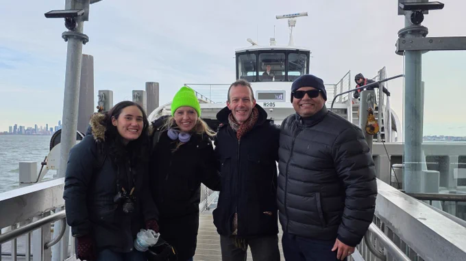 Deputy Public Advocate Hussain poses with community leaders on the dock in front of the ferry, all dressed for cold weather