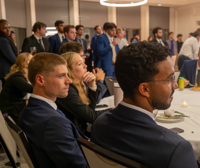 Stetson RGIP students in formal attire listening attentively at the showcase in Orlando.
